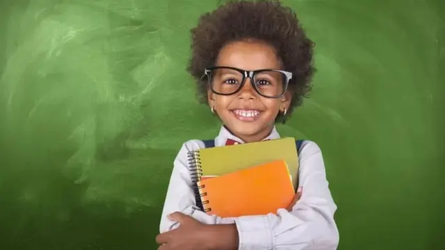 Criança sorridente com cadernos nas mãos