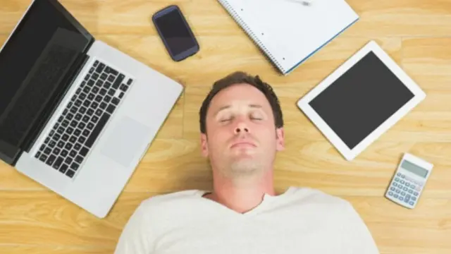 شاب ينام وحولة أجهزة لاب توب، وموبايل، وتابلت، وهاتف ذكي.