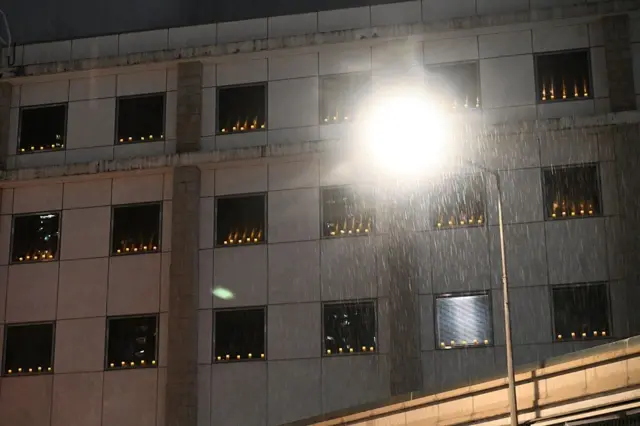 2025年6月4日晚，雨丝飘落，蜡烛点亮美国驻香港总领事馆的窗户。
