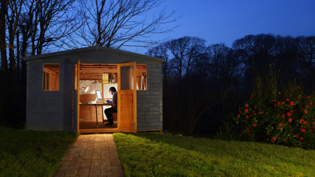 اتاقکی در باغچه یک خانه در هنگام شب و فردی درون آن