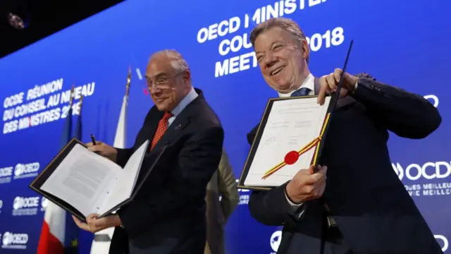 Juan Manuel Santos, presidente da Colômbia (à direita), mostra documento de adesão da Colômbia à OCDE