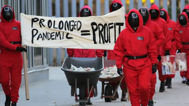 متظاهرون يرتدون زي شخصيات سكويد غايم أمام مقر شركة مودرنا في كامبريدج