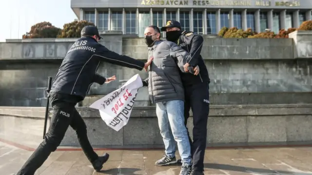 Полицейские на акции у парламента 28 декабря 2021 отбирают у журналиста плакат