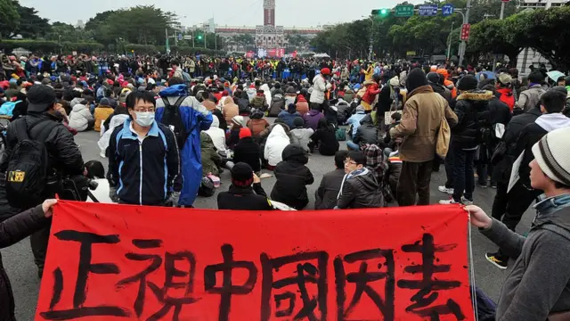 Students stage a sit-in protest and display a banner reading "Face up to the China factor", as they attend a flag-raising ceremony on New Year's Day at the Presidential Office Square in Taipei on January 1, 2013.