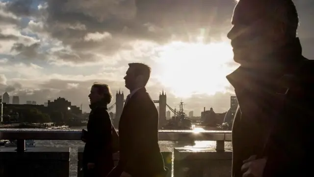 Personas caminando en contraluz, en el atardecer, en uno de los puentes de Londres