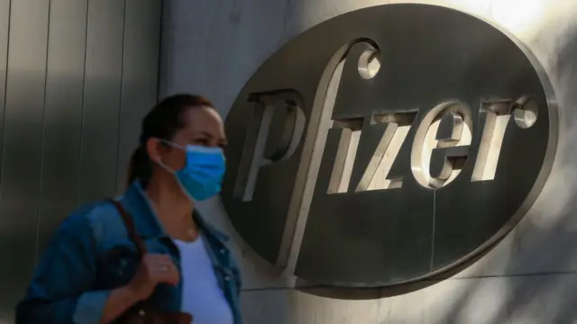 Woman walks past Pfizer sign