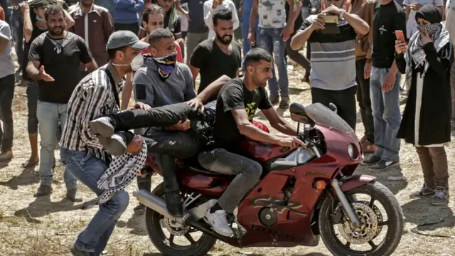 जखमी तरुणाला बाईवरून घेऊन जाताना.