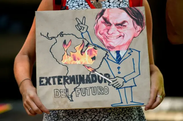 'Exterminador do futuro', diz cartaz que mostra Bolsonaro com um palitofósforo, incendiando a Amazônia. Cali (Colômbia), agosto2019