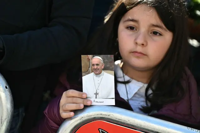 한 소녀 신자가 프란치스코 교황의 사진을 들고 추모하고 있다
