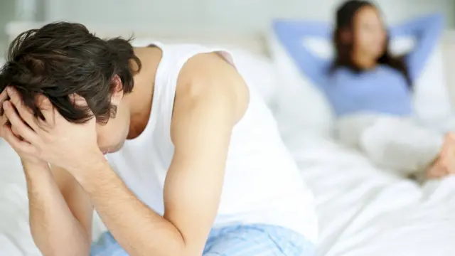 Homem sentado na beira da cama