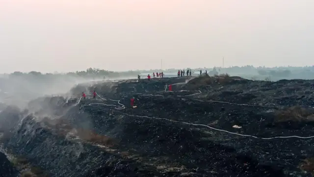 Personel gabungan berjibaku memadamkan api yang membara di bawah tumpukan sampah.