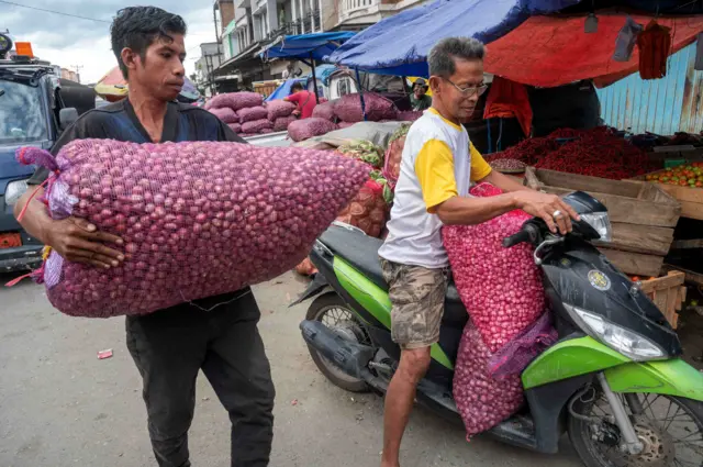 Pedagang membawa karung berisi bawang merah di Pasar Induk Manonda, Palu, Sulawesi Tengah, Kamis (19/12/2024). Harga bawang merah di wilayah itu naik hampir 100 persen dari rata-rata Rp21 ribu per kg pada pekan lalu menjadi Rp40 ribu per kg disebabkan tingginya permintaan jelang Natal dan tahun baru serta terganggunya distribusi akibat cuaca dari daerah penyuplai. 