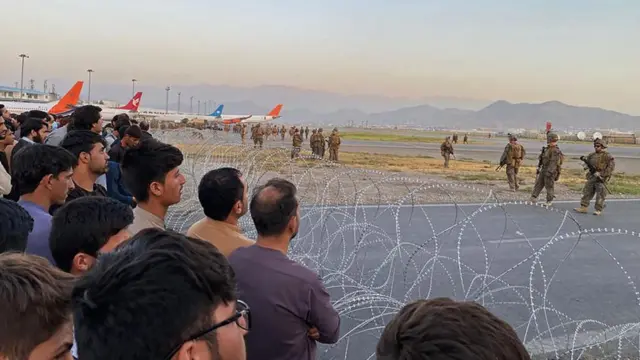 Soldados estadounidenses vigilan el aeropuerto de Kabul, mientras que civiles están separados por alambres de púas