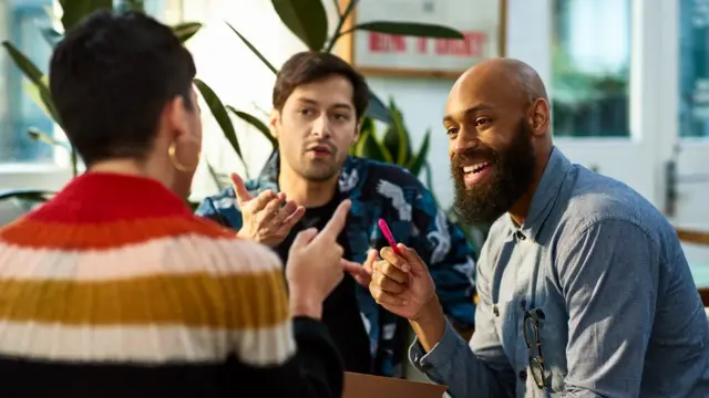 Tres personas conversan animadamente.