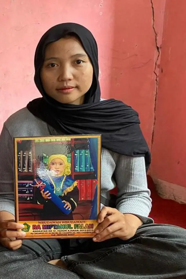 Kakak BR, Sindi, dengan foto adiknya kala masih kanak-kanak. BR baru mengeluhkan sakit kepala kepada kakaknya, Sindi, pada Senin (29/09).