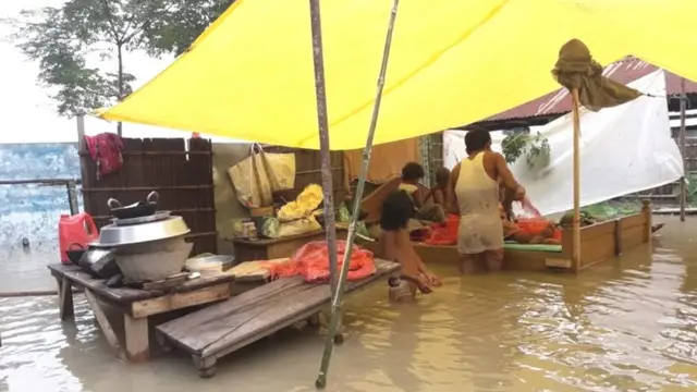 असम के दरांग ज़िले के एक गांव में बाढ़ के बीच एक परिवार