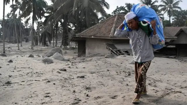 ছাইয়ে ডুবে যাওয়া বাড়ি থেকে মানুষজন যা পারেন উদ্ধারের চেষ্টা করছেন