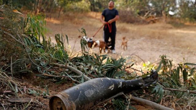 A man walks his dogs next to a destroyed missile