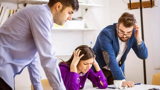 Tres personas sobre un escritorio, agobiadas por un problema laboral