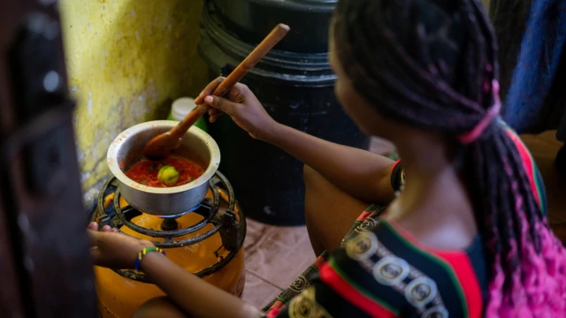 Mulher agachada cozinhandobaixar o aplicativo esporte da sortecimabaixar o aplicativo esporte da sortebotijão