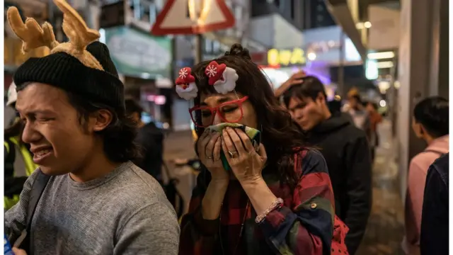 一些市民在警方发射催泪弹后掩脸离开。