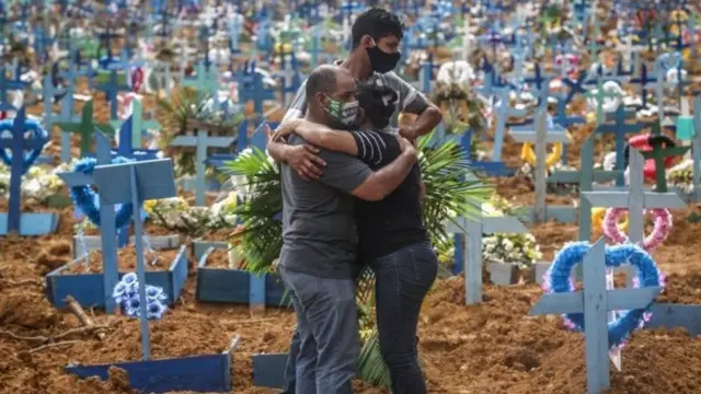 કબ્રસ્તાનમાં વ્યક્તિઓ ઊભેલી છે.