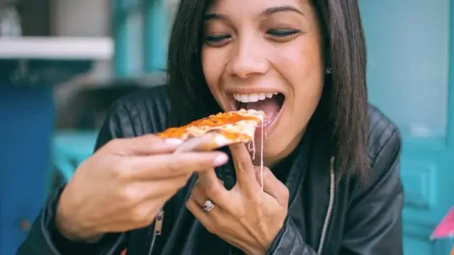પિઝ્ઝા ખાતી એક યુવતીની તસવીર
