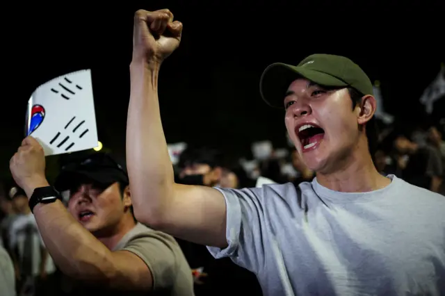 6일 서울의 한 개표소 앞에서 시위 참가자가 주먹을 들어 올리고 있다. 참가자들은 지방선거 과정에서 투표용지 부족으로 투표에 차질이 빚어진 데 항의하며 재선거를 요구했다.