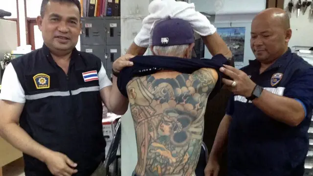This handout photo taken on January 10, 2018 and received by the Royal Thai Police shows retired Japanese crime boss Shigeharu Shirai (C), 72, being paraded to show his gang-style tattoos to reporters at a police station after his arrest in the central Thai province of Lopburi.