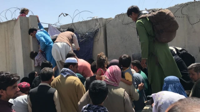 As pessoas tentam ultrapassar o muro do Aeroporto Internacional Hamid Karzai