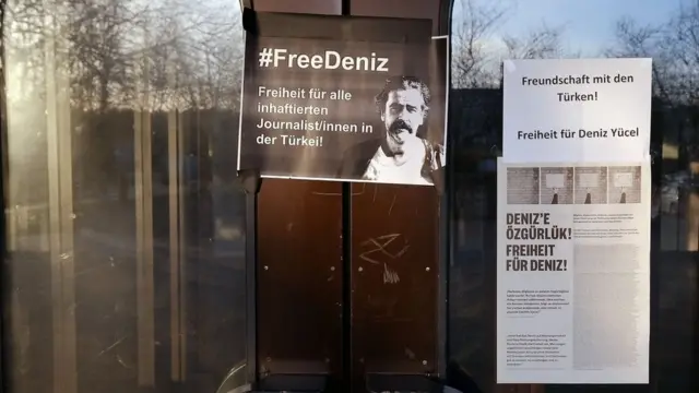 پوستر دنیز بوسل، خبرنگار آلمانی ترکیه‌ای بر در سالنی که قرار بود تجمع در آن برگزار شود