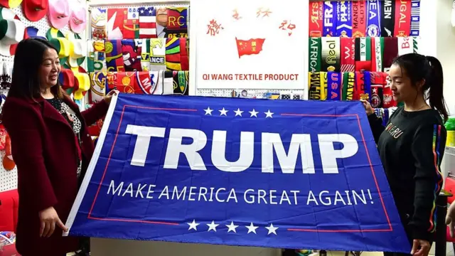 Dos mujeres chinas muestran una pancarta con el lema de la campaña de Trump.