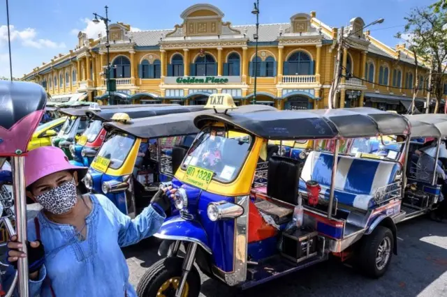 A tuk-tuk driver, wearing a facemask amid concerns about the spread of the COVID-19 novel coronavirus, waits for tourists in front of the Grand Palace in Bangkok on March 6, 2020