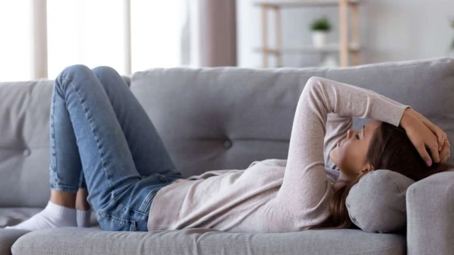 ภาพผู้หญิงนอนกุมหัวบนโซฟา