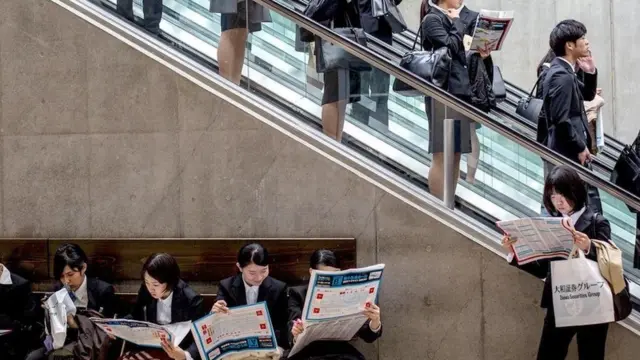 موظفون بقرأون جرائد في محطة للمترو