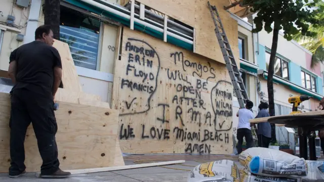Hombres tapiando puertas comercio.