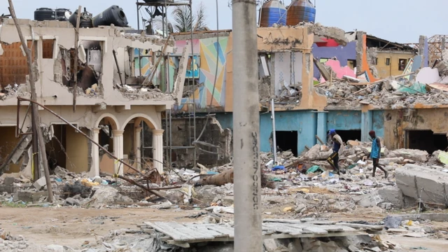 Pipo dey pick tins from di remains of one building wey destroy