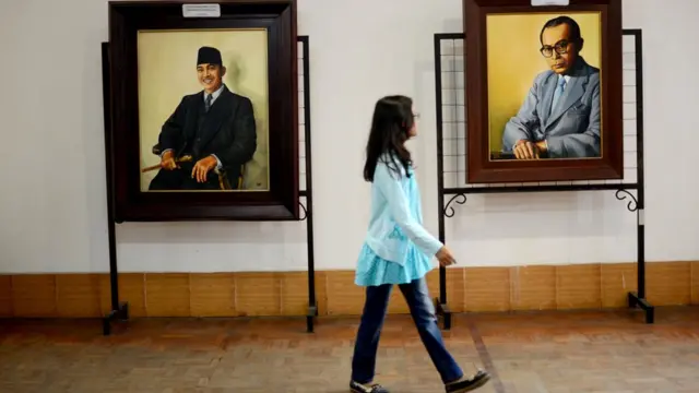 Seorang perempuan berjalan di depan lukisan Sukarno-Hatta di Blitar.