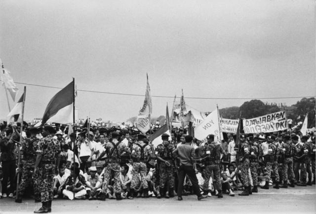 circa 1965: Indonesian troops bar a crowd of flag-waving students from the approach to president Achmed Sukarno's summer palace at Bogor in Indonesia following the abortive Communist coup of 1965.