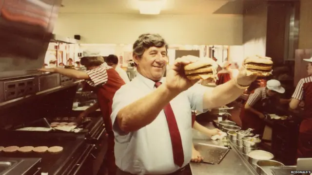 Michael "Jim" Delligatti con dos Big Mac en sus manos.