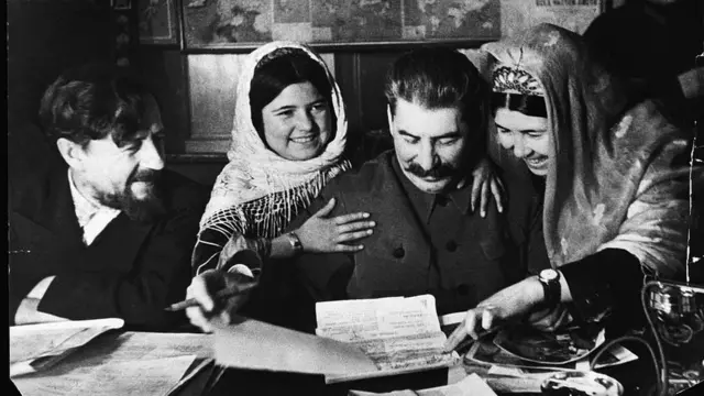 Women from a Tajik collective farm confer with Stalin and a people's commissar for agriculture in 1935
