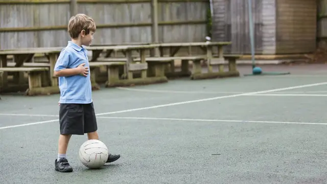 School boy playing on his own in playground