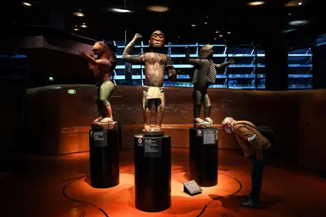 A visitor looks at statues of the Royal Treasures of the Abomey Kingdom at a museum in Paris, France, on Friday.