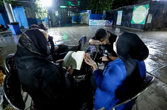Iranians wearing face masks as COVID-19 prevention attend ritual prayers in the rain, for Laylat al-Qadr (Night of Destiny) one of the holiest nights during the Muslim fasting month of Ramadan, outside the Imamzadeh Ainali-Zeinali mosque in the capital Tehran, on May 1, 2021. (Photo by ATTA KENARE / AFP) (Photo by ATTA KENARE/AFP via Getty Images)