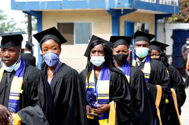 Student stand in a line durign a graduation ceremony.