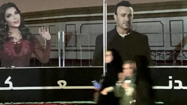 Mata na wuce babban allon dauke da hotunan mawakan a kan hanya