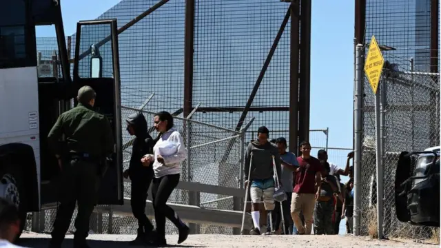 Migrantes son llevados a un autobús por autoridades de EE.UU.