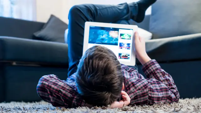 Niño acostado en el suelo con una tableta
