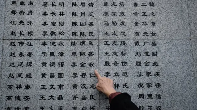 侵华日军南京大屠杀遇难同胞纪念馆一名遇难者遗属指着“哭墙”上新增的姓名（新华社图片10/12/2016）