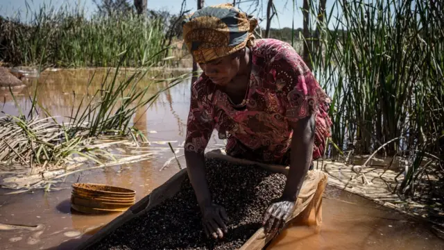 Mulher separa cobaltosaque h2betlama e pedras pertosaque h2betuma mina na República Democrática do Congo